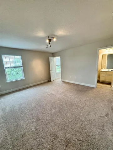 an empty room with windows and chandelier fan