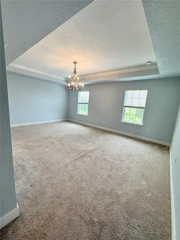 an empty room with windows and chandelier