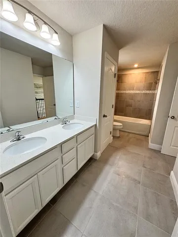 a spacious bathroom with a double vanity sink a large mirror and a bathtub
