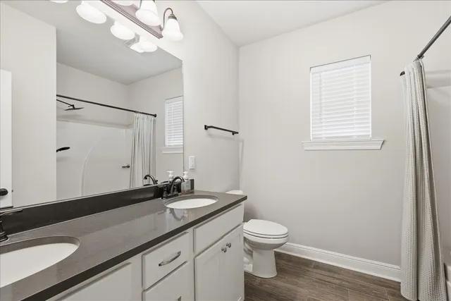 a bathroom with a granite countertop sink a toilet and a mirror
