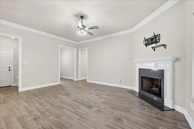 a view of empty room with wooden floor fireplace and fan