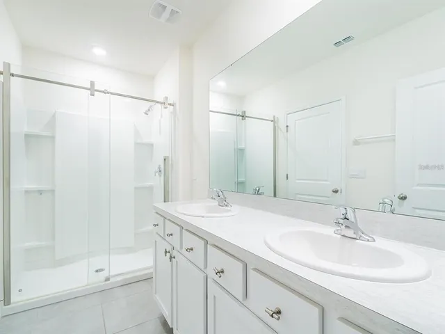 a bathroom with a shower sink vanity and mirror