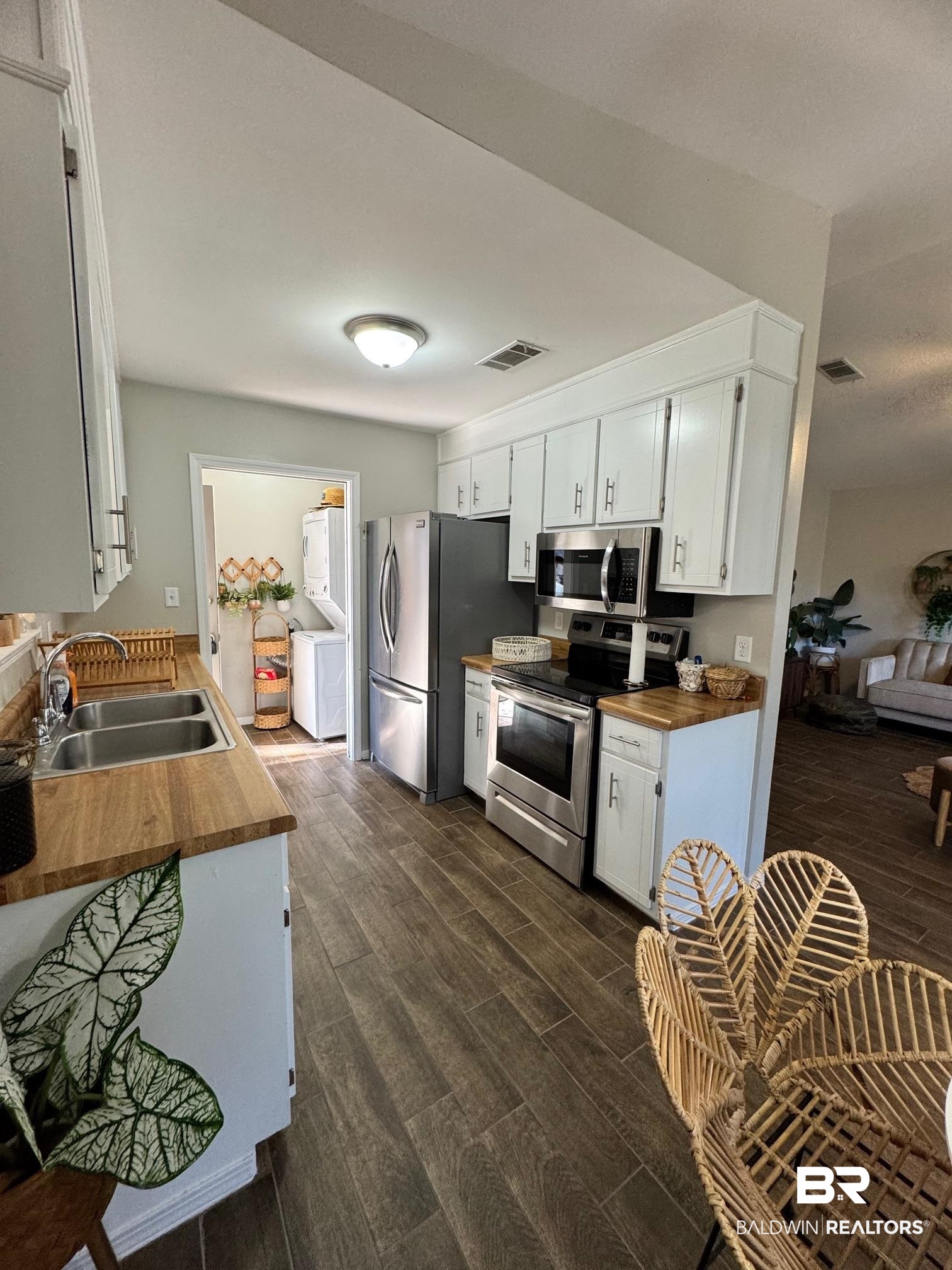 1434 Ridgewood Drive Lillian, AL 36549 - Photo 11 of 45 Kitchen featuring white cabinetry, sink, stainless steel appliances, and dark hardwood / wood-style floors