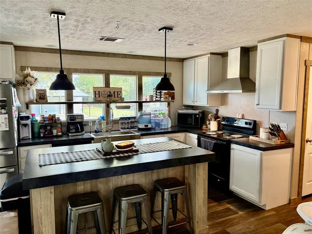 a kitchen with stainless steel appliances granite countertop a sink a stove and a wooden floors