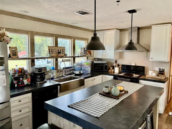 a kitchen with stainless steel appliances a stove a sink a refrigerator and chairs