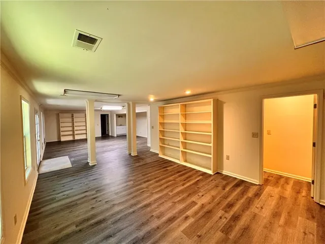 a view of an empty room with a window and wooden floor