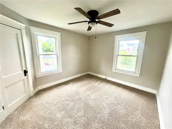 an empty room with a window and a fan