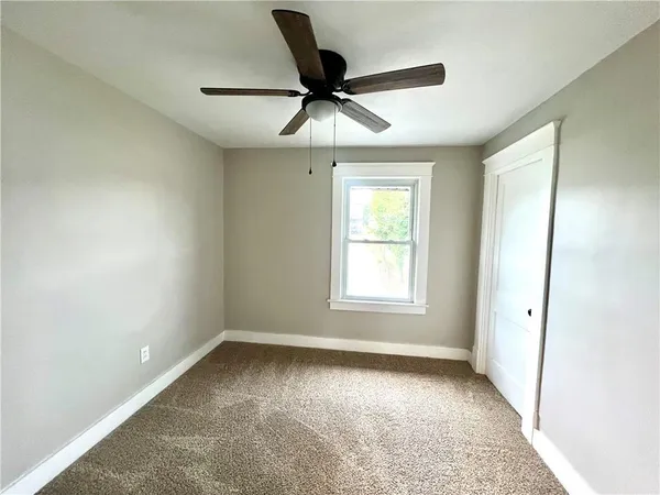 an empty room with ceiling fan and window
