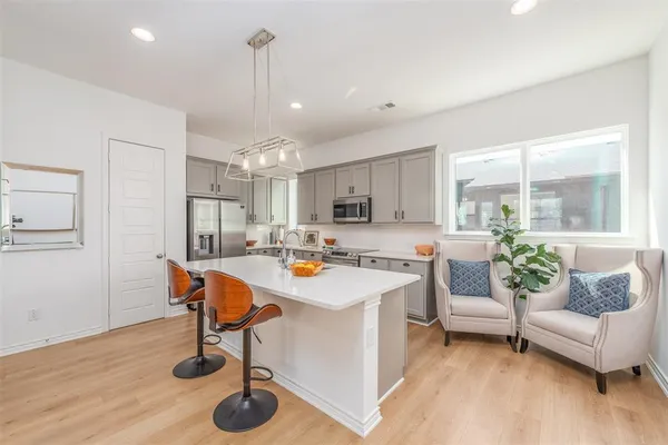 a kitchen with stainless steel appliances a white stove top oven a sink dishwasher and white cabinets with wooden floor