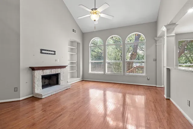 wooden floor fireplace and windows in an empty room