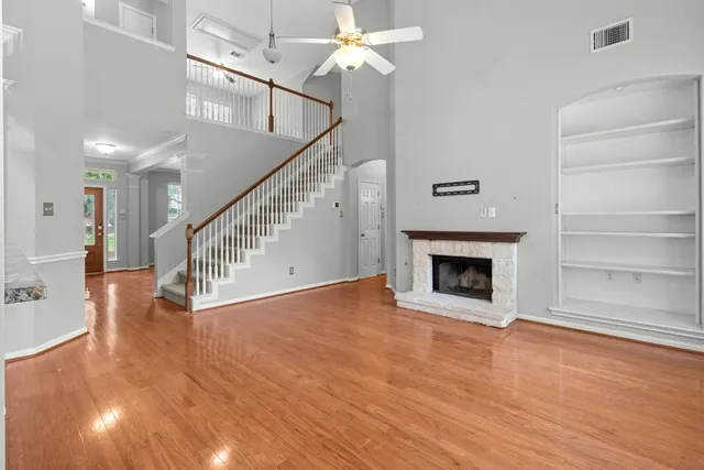 a view of a livingroom with wooden floor a ceiling fan and staircase