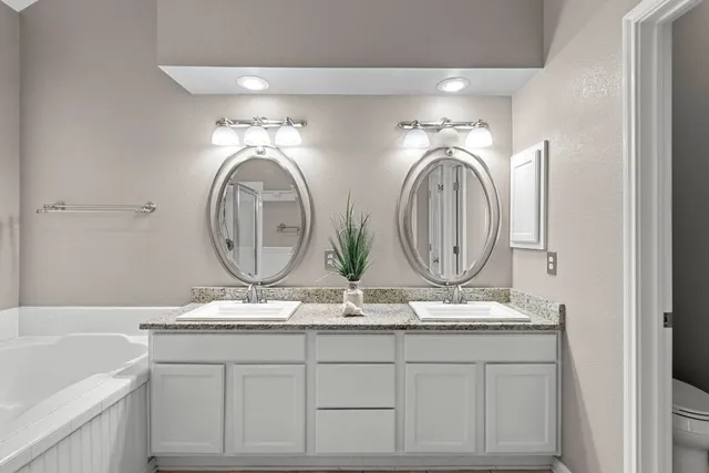 a bathroom with a granite countertop bathtub sink vanity and mirror