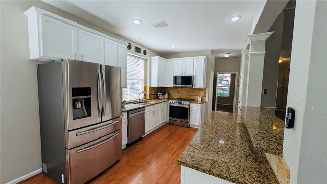 a kitchen with granite countertop stainless steel appliances a refrigerator counter top space and cabinets
