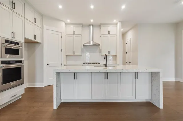 a kitchen with kitchen island granite countertop white cabinets and stainless steel appliances