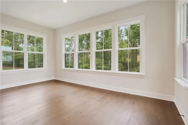 a view of an empty room with wooden floor and windows