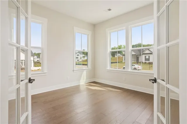 a view of an empty room with a window and wooden floor