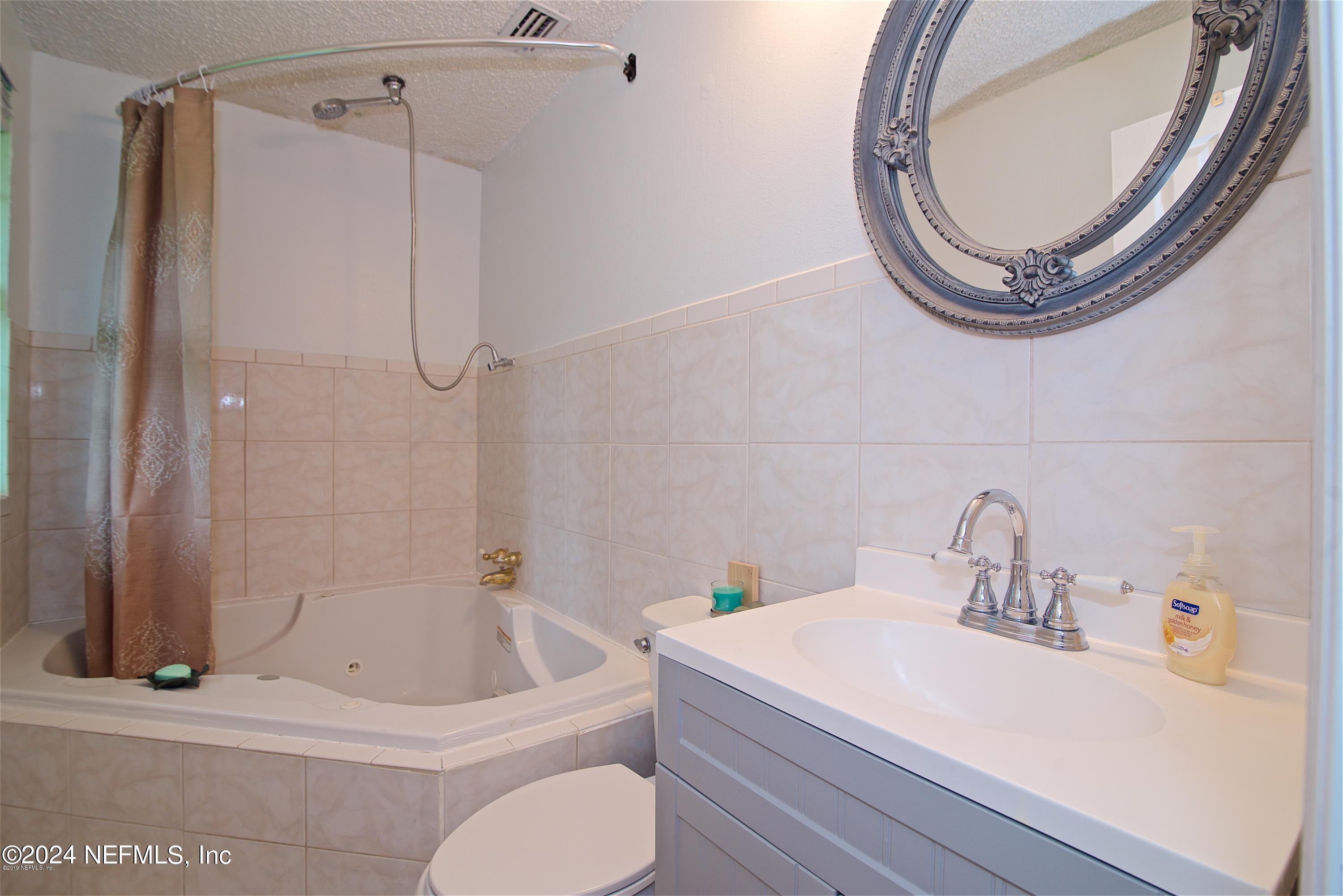 1938 Biggers Road Jacksonville, FL 32216 - Photo 24 of 25 a bathroom with a sink a toilet and a mirror
