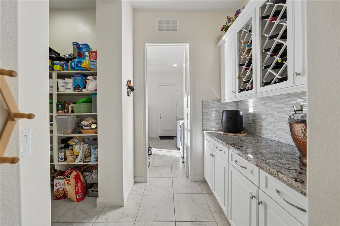 7774 Kingdom Drive Riverside, CA 92506 - Photo 23 of 66 Additional prep and storage space includes built-in cabinetry, countertop workspace, wine storage, and a large walk-in pantry.