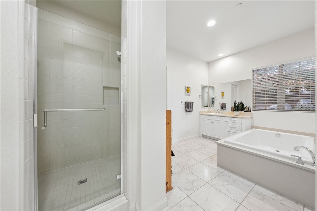 7774 Kingdom Drive Riverside, CA 92506 - Photo 31 of 66 a bathroom with a bathtub a sink a mirror and a shower