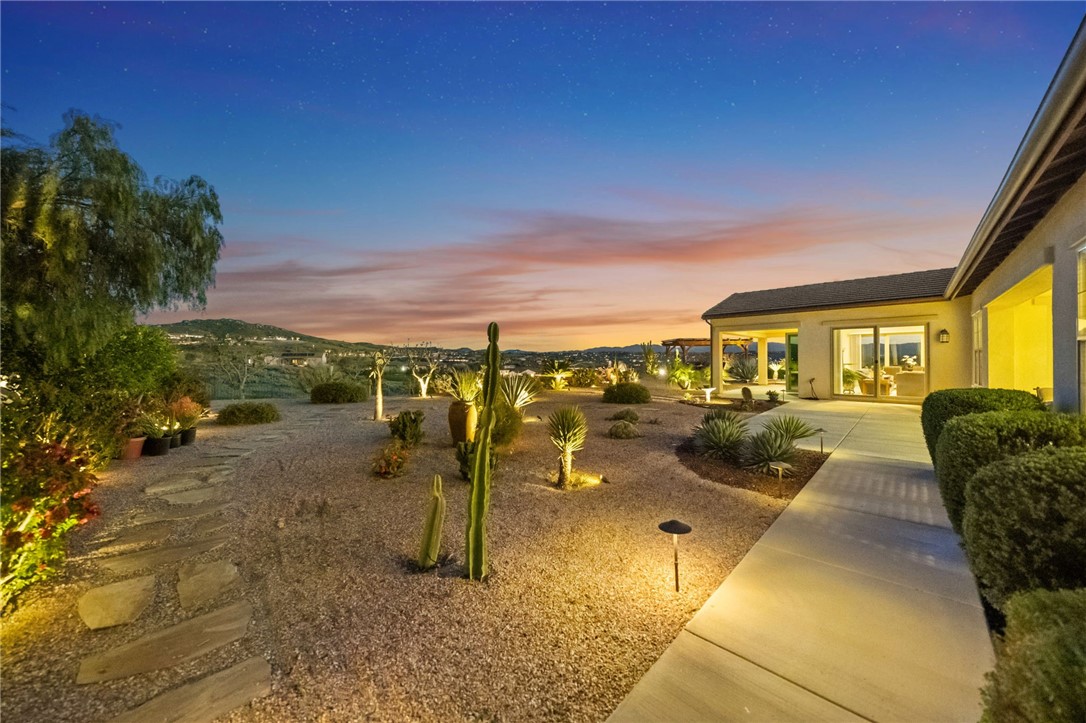 7774 Kingdom Drive Riverside, CA 92506 - Photo 64 of 66 Illuminated desert landscaping and stone pathways create a striking backyard ambiance at dusk with wide-open hillside views.