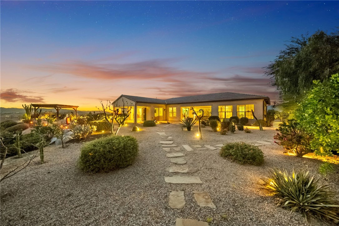 7774 Kingdom Drive Riverside, CA 92506 - Photo 9 of 66 Resort-style backyard with illuminated landscape lighting, gravel hardscape, and a spacious patio area designed for relaxing evenings outdoors.