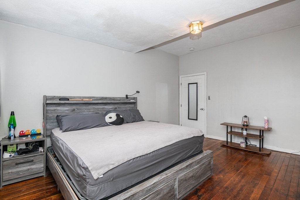 96 Derby Street, Unit 1 Salem, MA 01970 - Photo 14 of 31 a bedroom with a bed and a dresser with wooden floor