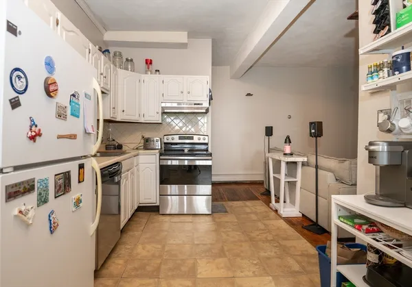 a kitchen with stainless steel appliances granite countertop a sink a stove a refrigerator and white cabinets