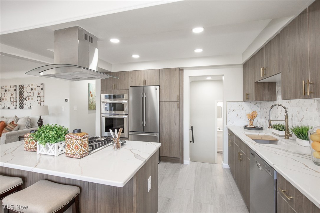 4631 Belfiore Road Cleveland, OH 44128 - Photo 28 of 28 Kitchen featuring light stone counters, island exhaust hood, recessed lighting, appliances with stainless steel finishes, and open floor plan