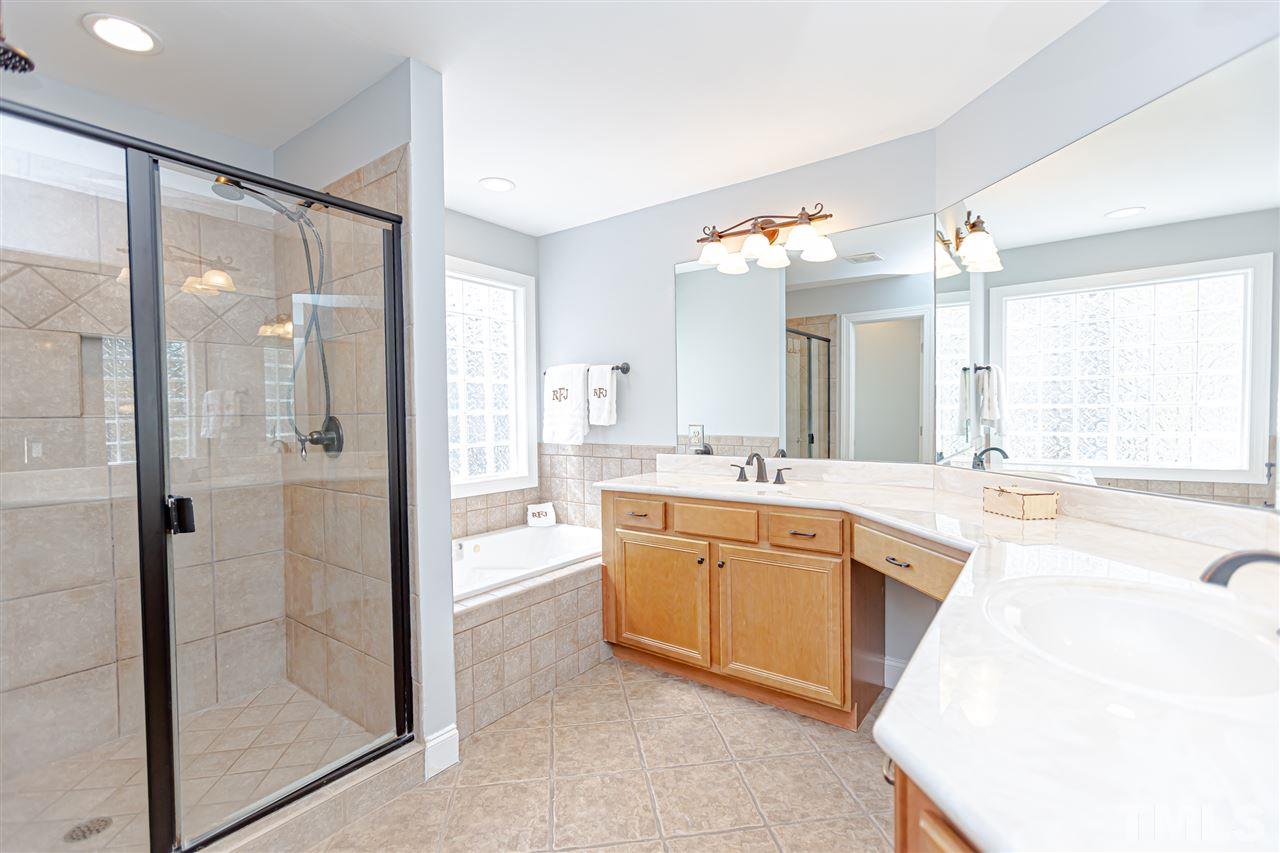 9408 Ray Road Raleigh, NC 27613 - Photo 18 of 30 a large bathroom with a large mirror vanity and shower