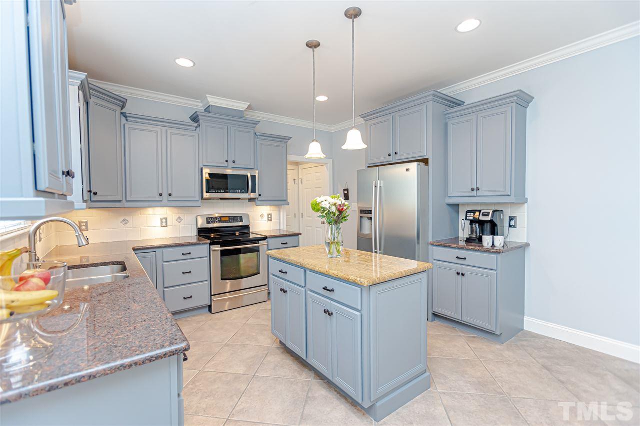 9408 Ray Road Raleigh, NC 27613 - Photo 10 of 30 a kitchen with granite countertop a refrigerator oven a sink dishwasher and white cabinets with wooden floor