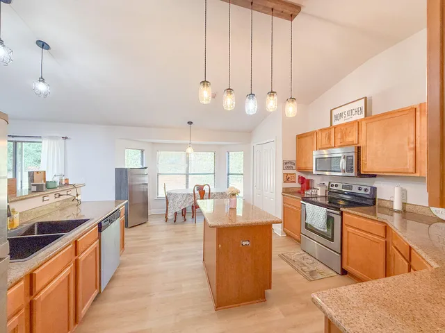 a large kitchen with kitchen island a large counter top space a sink stainless steel appliances and cabinets