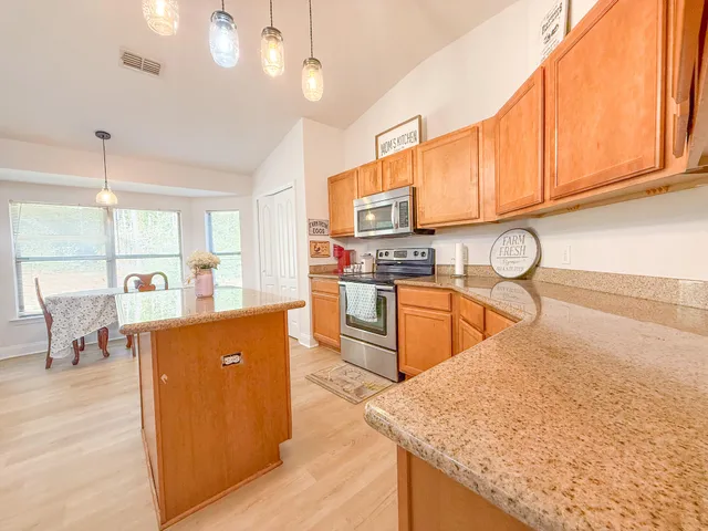 a kitchen with stainless steel appliances granite countertop a sink a stove and a wooden floors with cabinets