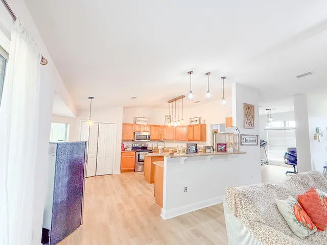 a view of a kitchen with kitchen island stainless steel appliances wooden cabinets and living room view
