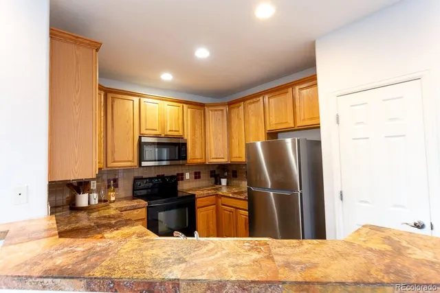 a kitchen with granite countertop a refrigerator and a stove top oven