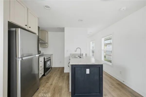 a kitchen with stainless steel appliances granite countertop a refrigerator a sink and white cabinets
