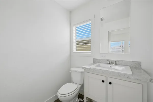 a bathroom with a granite countertop toilet a sink a mirror and a window