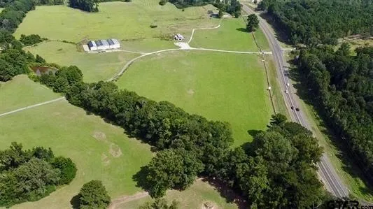 an aerial view of a residential houses with outdoor space and trees all around