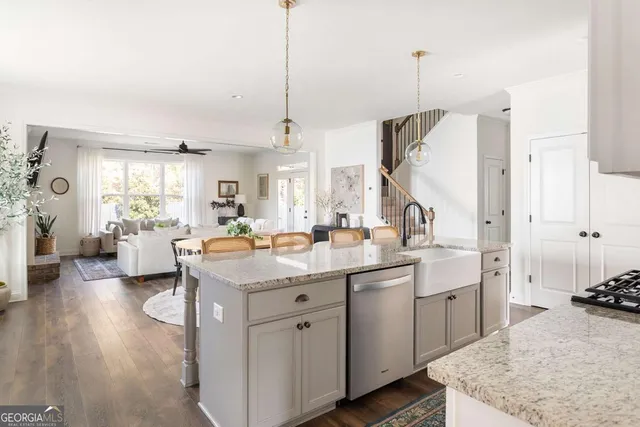 a kitchen with stainless steel appliances granite countertop a sink a stove and a wooden floor