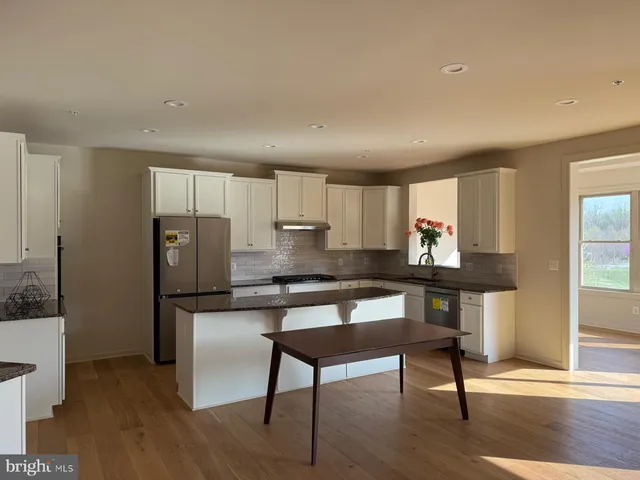 a kitchen with stainless steel appliances wooden floor and chair