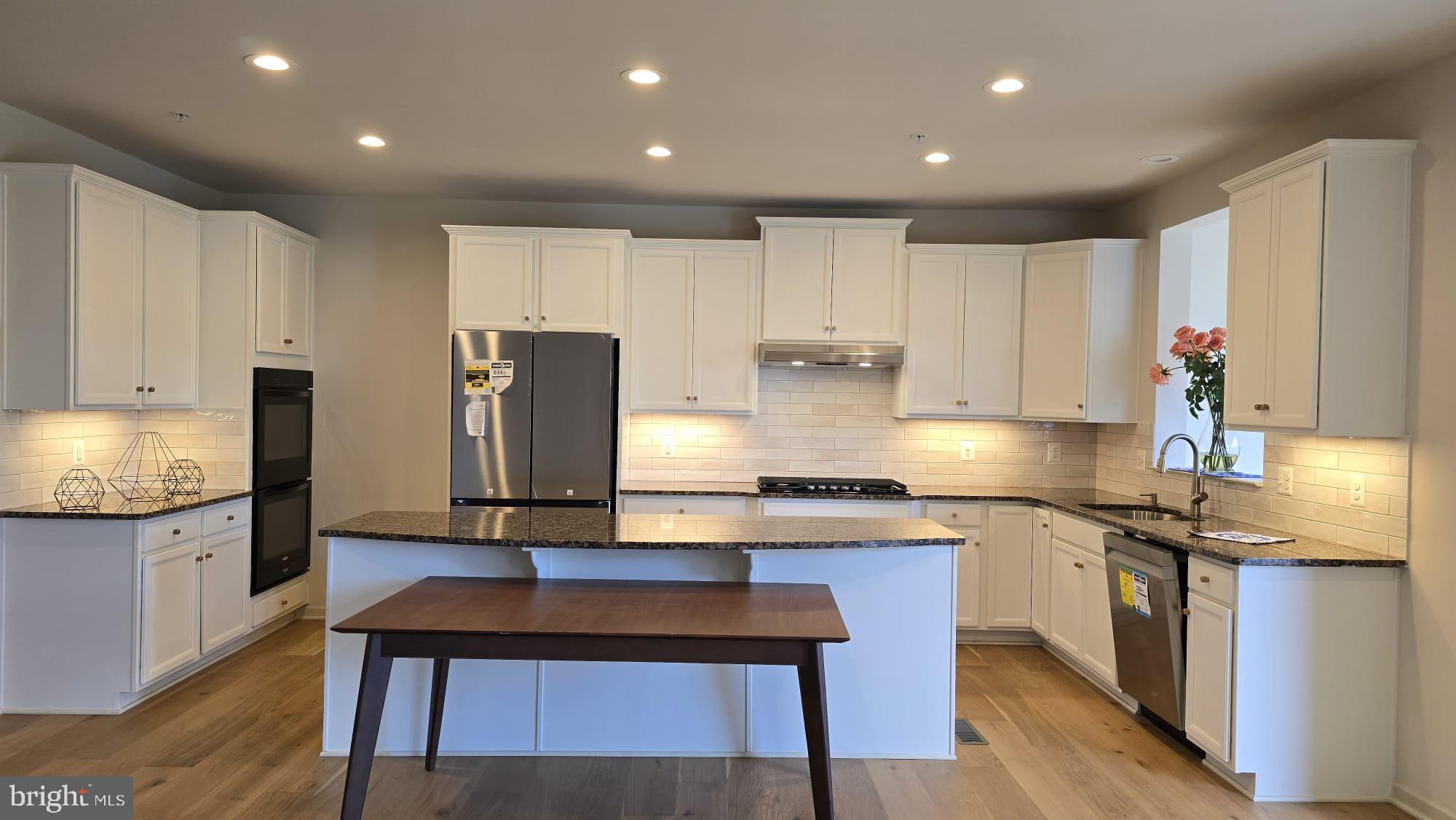 1108 Autumn Brook Avenue Silver Spring, MD 20906 - Photo 3 of 68 a large kitchen with stainless steel appliances granite countertop a stove a sink a refrigerator and white cabinets with wooden floor
