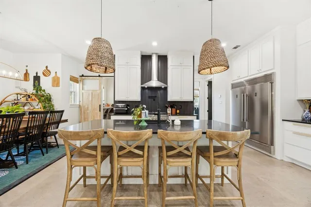 a kitchen with stainless steel appliances a dining table chairs and white cabinets
