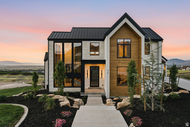 923 North Emery Lane Elk Ridge, UT 84651 - Photo 2 of 101 Contemporary exterior featuring a black metal roof, vertical wood-finish siding, light-colored stone veneer, and extensive black-framed windows