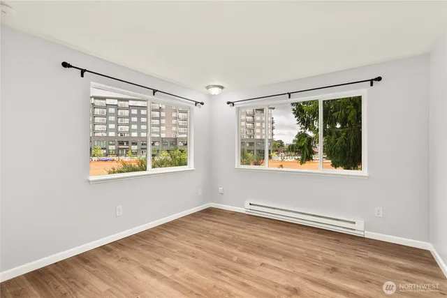 an empty room with wooden floor and windows