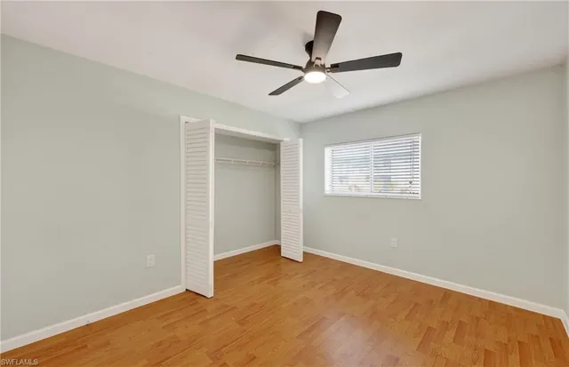a view of a big room with wooden floor closet ceiling fan and windows