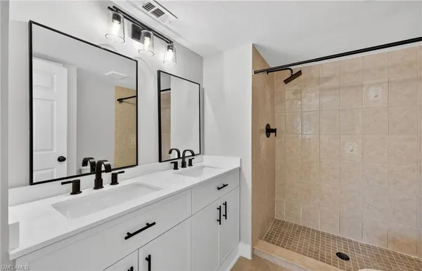a bathroom with a double vanity sink mirror and shower