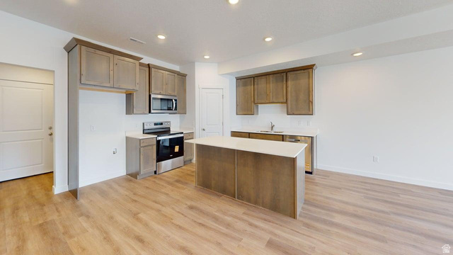 777 Pheasantbrook Drive, Unit 2B Centerville, UT 84014 - Photo 7 of 42 Kitchen featuring wood-finish flooring, shaker-style cabinetry, stainless steel appliances, a center island with a white countertop, and recessed lighting