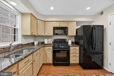 a kitchen with granite countertop a refrigerator stove and sink