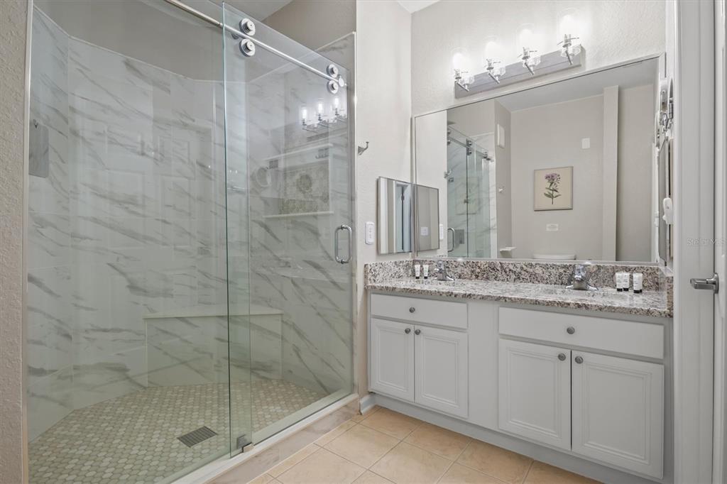 301 Terrace Ridge Circle, Unit 301 Davenport, FL 33896 - Photo 14 of 35 a bathroom with a granite countertop sink a mirror and shower