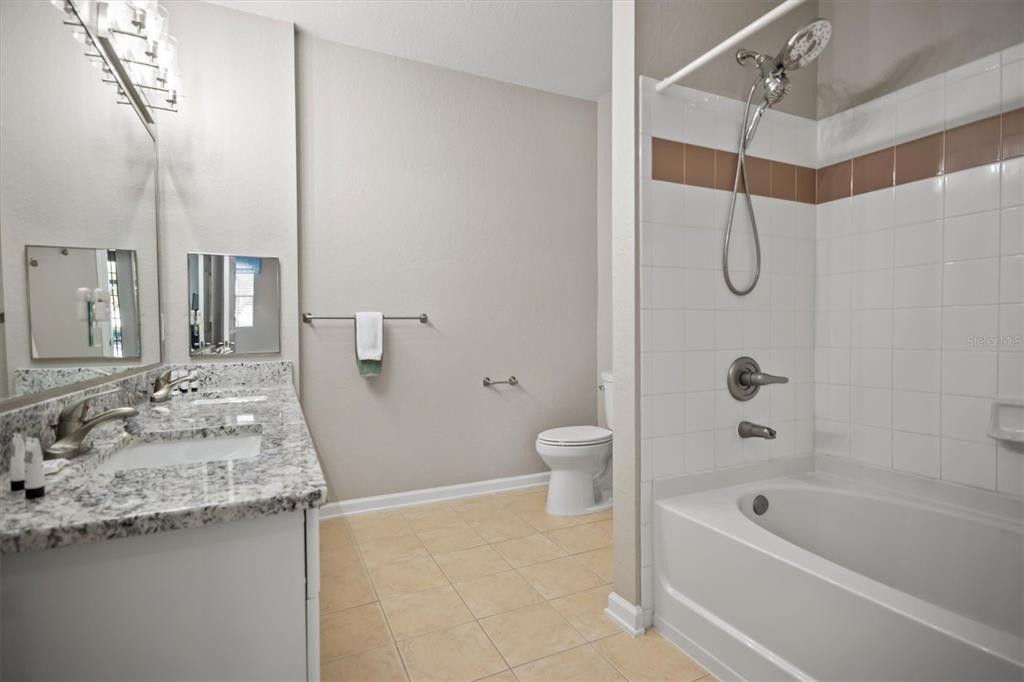 301 Terrace Ridge Circle, Unit 301 Davenport, FL 33896 - Photo 17 of 35 a bathroom with a granite countertop sink a toilet and shower