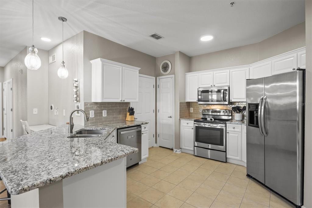 301 Terrace Ridge Circle, Unit 301 Davenport, FL 33896 - Photo 3 of 35 a kitchen with kitchen island granite countertop a sink stove and refrigerator
